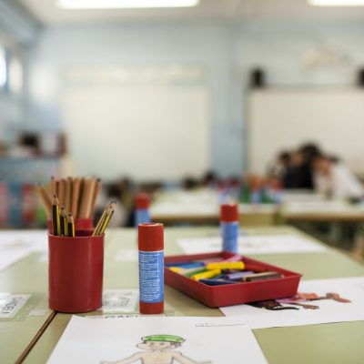 pens, paints and glue stick on table in a primary school class